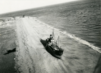 A vessel run aground on the shingle. Part of the gravel extraction plant is visible in the distance.